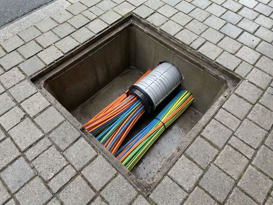 Geöffneter Kabelschacht mit Mikrorohren im Gehweg